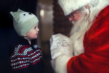 Santa reads a letter from a child in a fox hat.